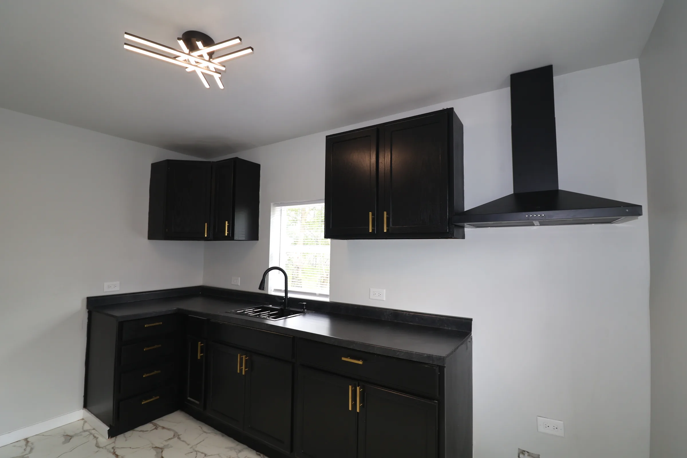 Finished kitchen with black cabinets and gold hardware
